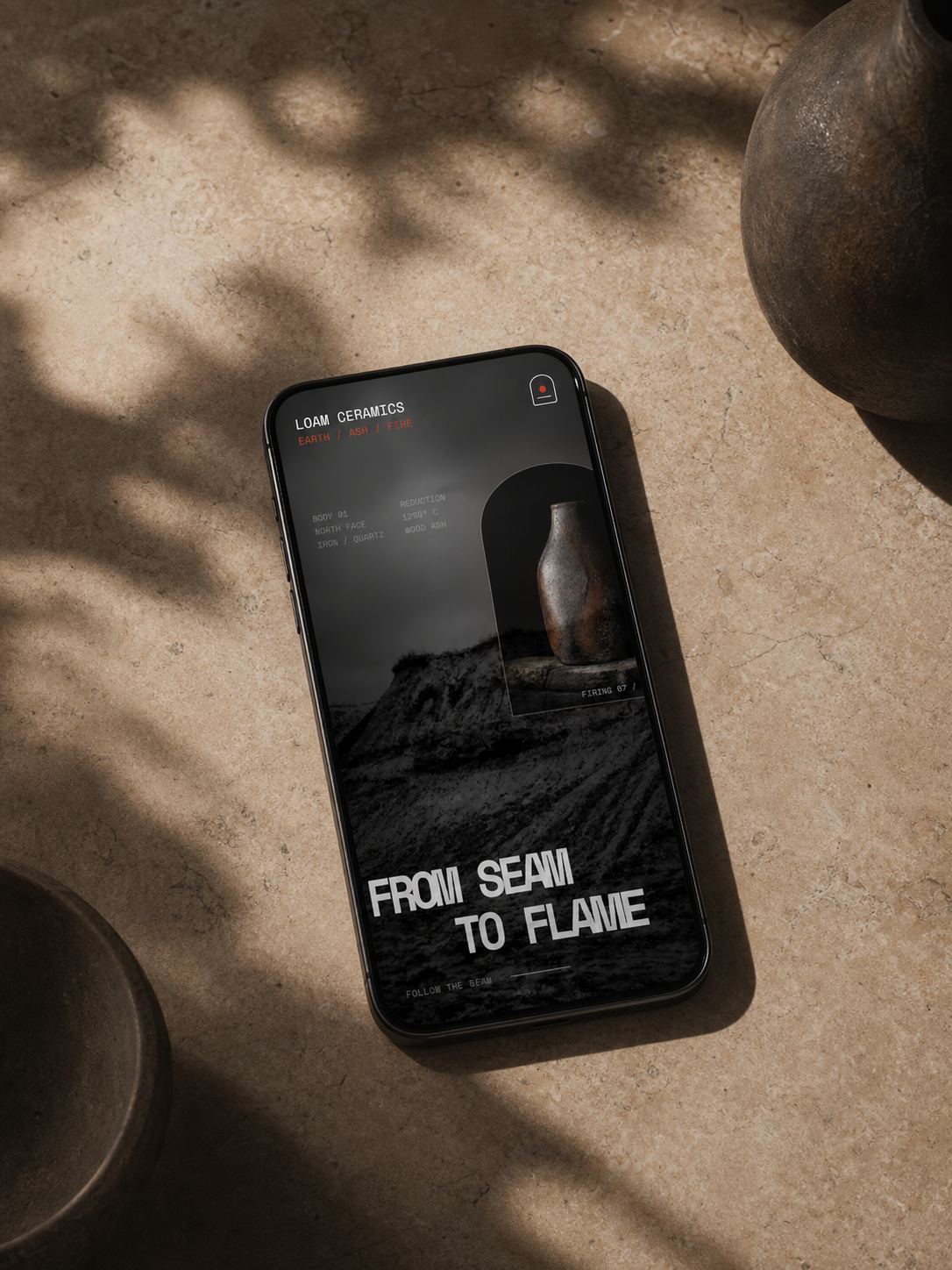 LOAM mobile homepage displayed on a phone in a warm ceramics studio